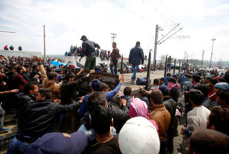 Migrants and refugees push back a train carriage after unsuccessful attempt to push it on the rail tracks leading to Macedonia at a makeshift camp at the Greek-Macedonian border near the village of Idomeni, Greece, April 11, 2016. REUTERS/Stoyan Nenov