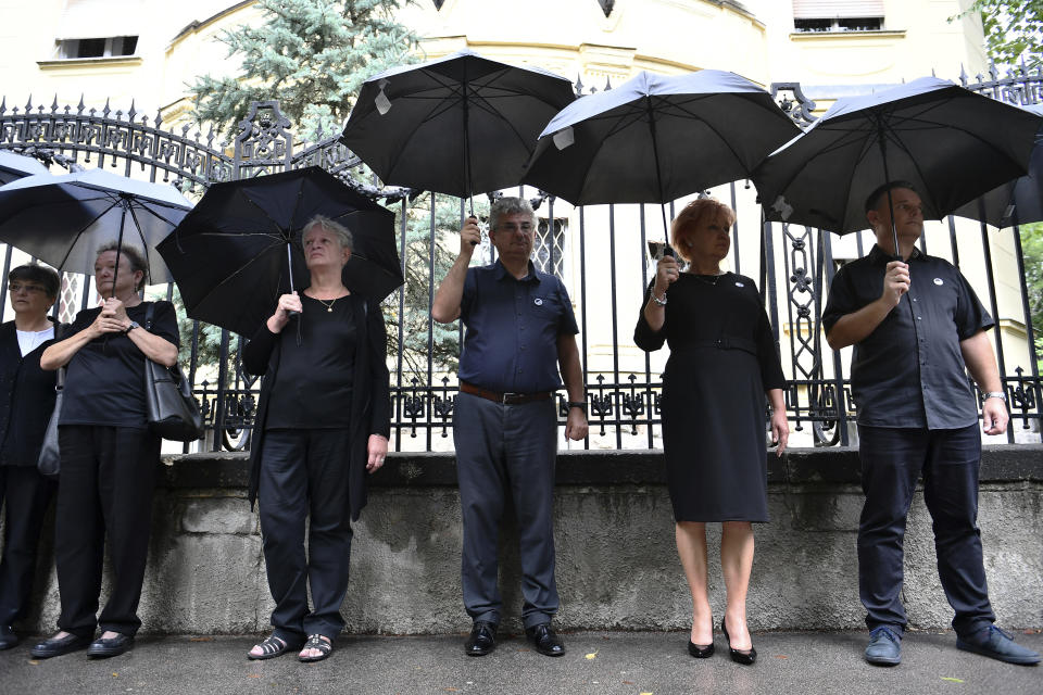 FILE - Members of Hungary's Teachers' Union (PSZ) stand during a protest, at a school year opening event, with black umbrellas over their heads to signify the problems of education, in Budapest, Hungary, Thursday, Sept. 1, 2022. Public schools in Poland and Hungary are facing a shortage of teachers at a time when both countries are taking in many Ukrainian refugee children. For years, teachers have been fleeing public schools over grievances regarding low wages and a sense of not being valued by their governments. (AP Photo/Anna Szilagyi, File)