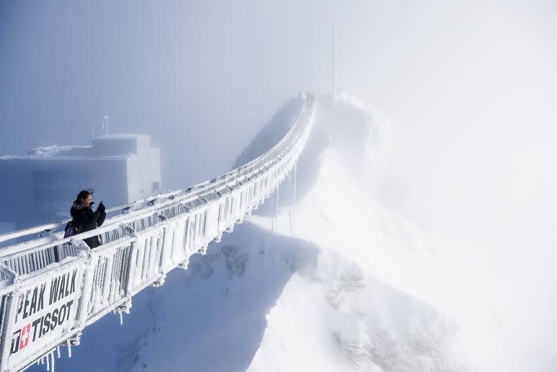 Snowier times: A tourist takes a photo from the "Peak Walk" suspension bridge on a winter day at the Glacier 3000 ski resort in Switzerland