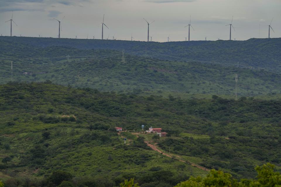 Wind turbines are visible in the distance of Sumidouro, Piaui state, Brazil, Wednesday, March 13, 2024. Wind energy is booming in Brazil's Northeast, but some projects are drawing criticism as it becomes clear that certain communities have benefited while others have not. (AP Photo/Andre Penner)