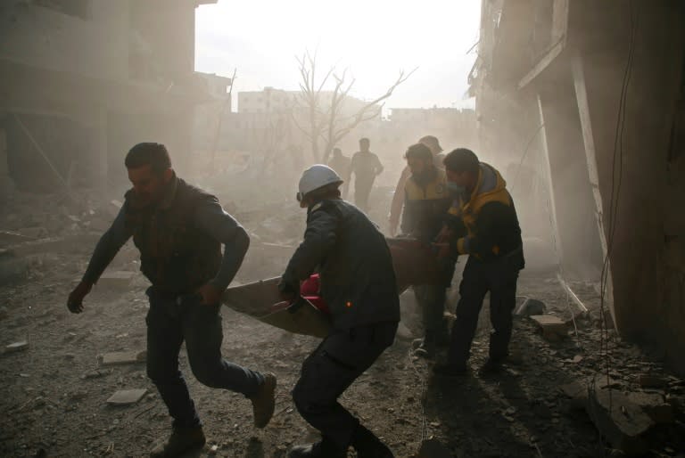 White Helmets evacuate a victim of an air strike in the rebel-held enclave of Eastern Ghouta in Syria