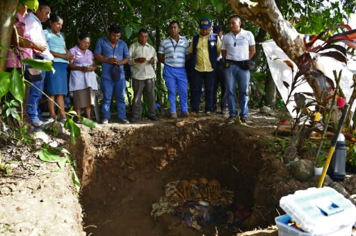 Local residents pray as the human remains -- said to be victims of El Salvador's infamous 1981 Mozote massacre -- were exhumed