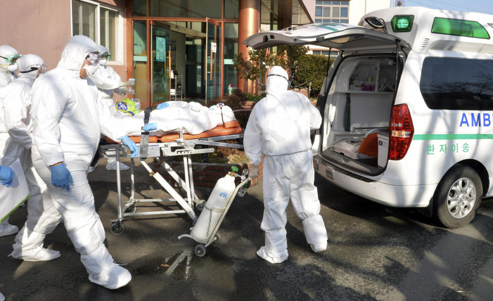 Medical workers wearing protective gears carry a patient suspected of contracting the new coronavirus toward an ambulance at Daenam Hospital in Cheongdo, South Korea, Friday, Feb. 21, 2020. South Korea reported 100 new virus cases Friday, bringing the country's total to 204, many of them clustered around a southeastern city, and raising fears that the outbreak is getting out of control. (Lee Moo-ryul/Newsis via AP)