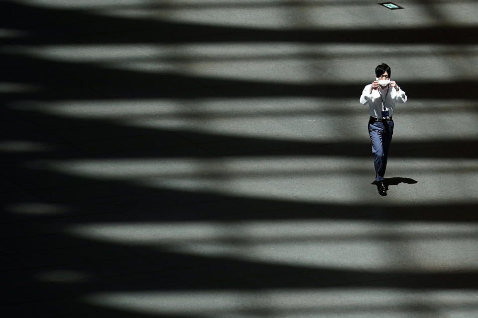 A man adjusts a protective mask to help curb the spread of the new coronavirus as he walks in the shade of a building Wednesday, June 10, 2020, in Tokyo. Hot weather continues in the metropolitan area as the temperature may rise to about 31 degrees Celsius (about 87.9 degrees Fahrenheit), according to Japan's meteorological bureau. (AP Photo/Eugene Hoshiko)