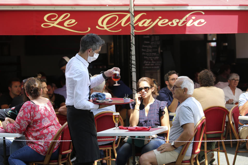 Un mesero le sirve un trago a una clieta en un café de Saint Jean de Luz, en el sur de Francia, el martes 2 de junio de 2020. (AP Foto/Bob Edme)