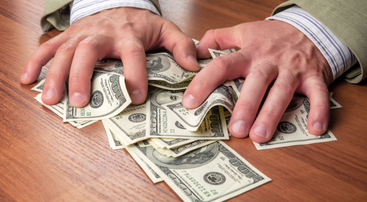 man's hand holding wads of cash