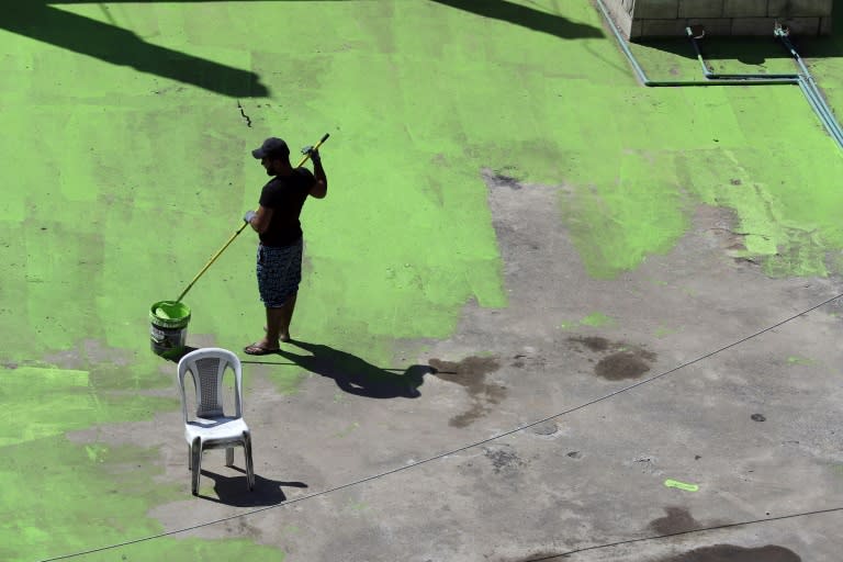 A Lebanese painter works on a rooftop on September 28, 2017 as part of a project to write the word "peace" in Arabic across 85 buildings in a Tripoli street dividing rival Sunni and Alawite-majority nneighbourhoods