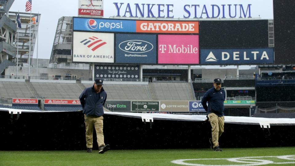 Jun 1, 2022; Bronx, New York, USA; Members of the grounds crew pull the tarp across the field after batting practice before a game between the New York Yankees and the Los Angeles Angels at Yankee Stadium. Mandatory Credit: Brad Penner-USA TODAY Sports