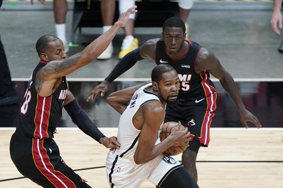 Brooklyn Nets forward Kevin Durant, center, goes up for a shot against Miami Heat forward Andre Iguodala, left, and guard Kendrick Nunn, right, during the first half of an NBA basketball game, Sunday, April 18, 2021, in Miami. (AP Photo/Wilfredo Lee)