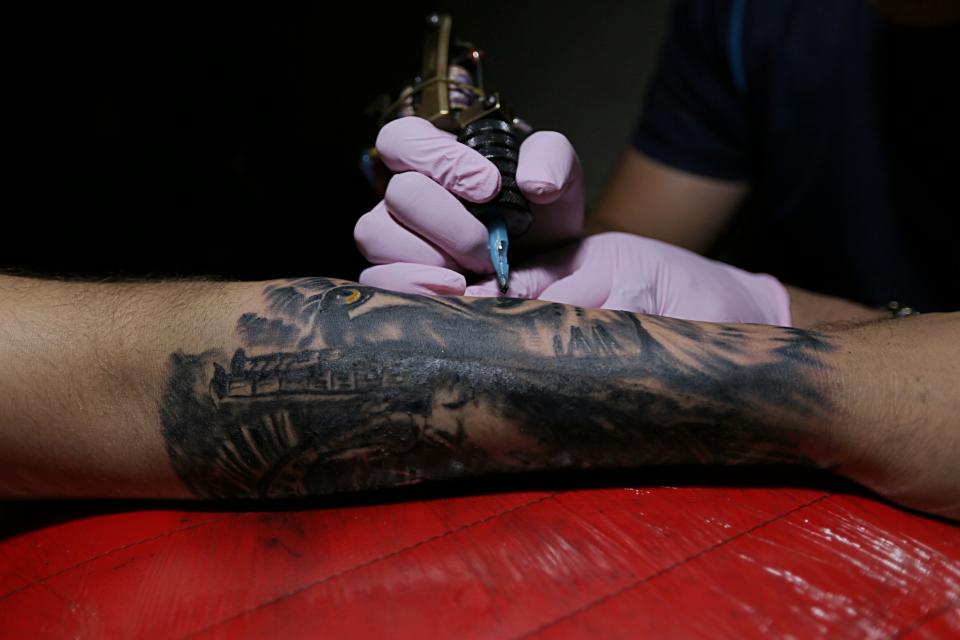 In this Saturday, Oct. 20, 2018, photo, Iraqi soldier Ziad Emad gets a tattoo on his arm to cover the wounds he suffered in the battle to oust the Islamic State group from Mosul, at a tattoo studio in Baghdad, Iraq. Aboud Abbas, who owns a tattoo studio, said he receives an average of 20 persons a year who want to cover their scars with tattoos, a nearly 30 percent increase from last year. (AP Photo/Hadi Mizban)