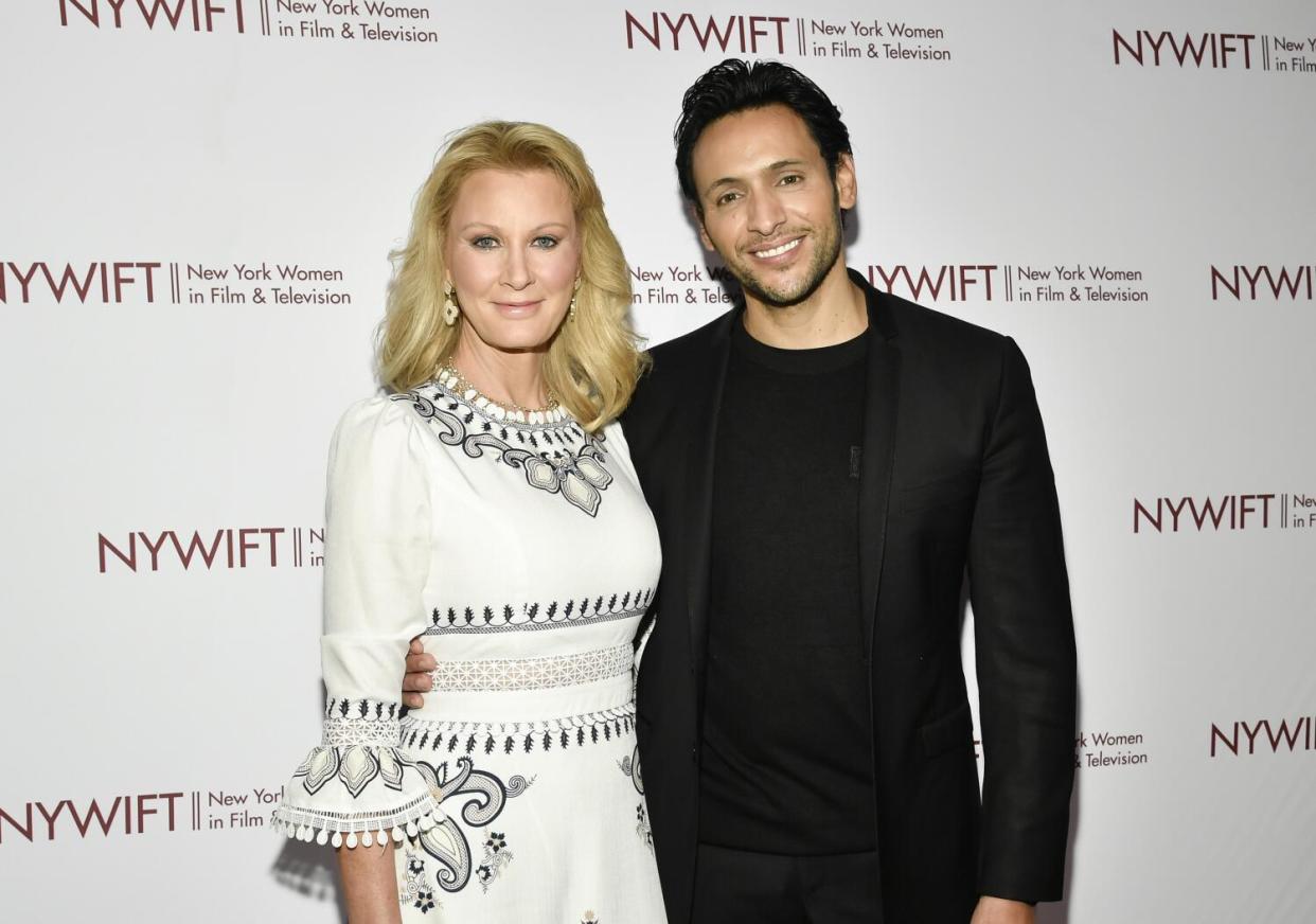 Sandra Lee in a white dress with black embroidery stands next to Ben Youcef in front of white backdrop.