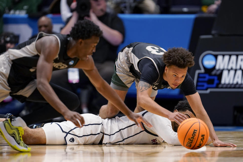 Wagner's Julian Brown (13) and Melvin Council Jr., left, dive for a loose ball as Howard's Seth Towns watches during the first half of a First Four college basketball game in the men's NCAA Tournament on Tuesday, March 19, 2024, in Dayton, Ohio. (AP Photo/Jeff Dean)