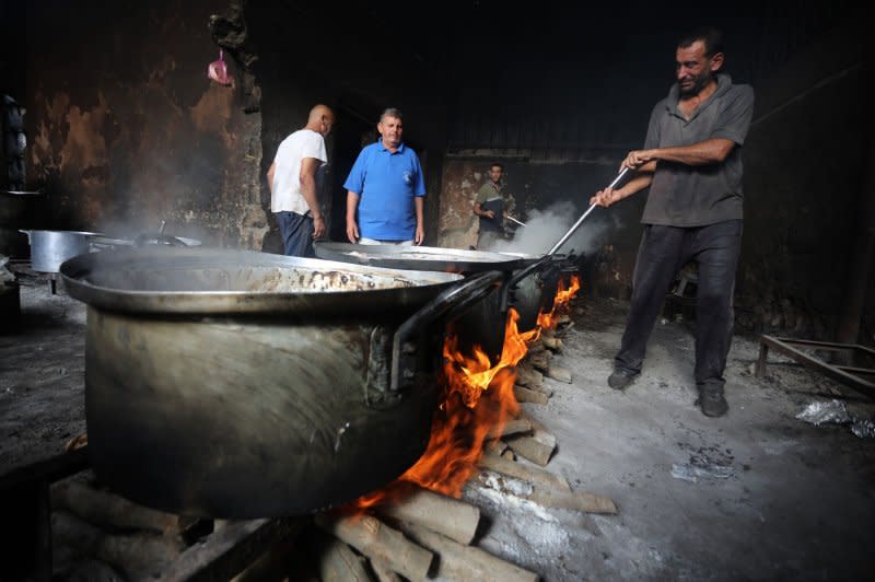 Palestinian men prepare food in large pots simmering on wooden fires due to the lack of cooking gas in Rafah in the southern Gaza Strip on Saturday as Israel announced the war had entered a 'new phase.' Photo by Ismael Mohamad/UPI.