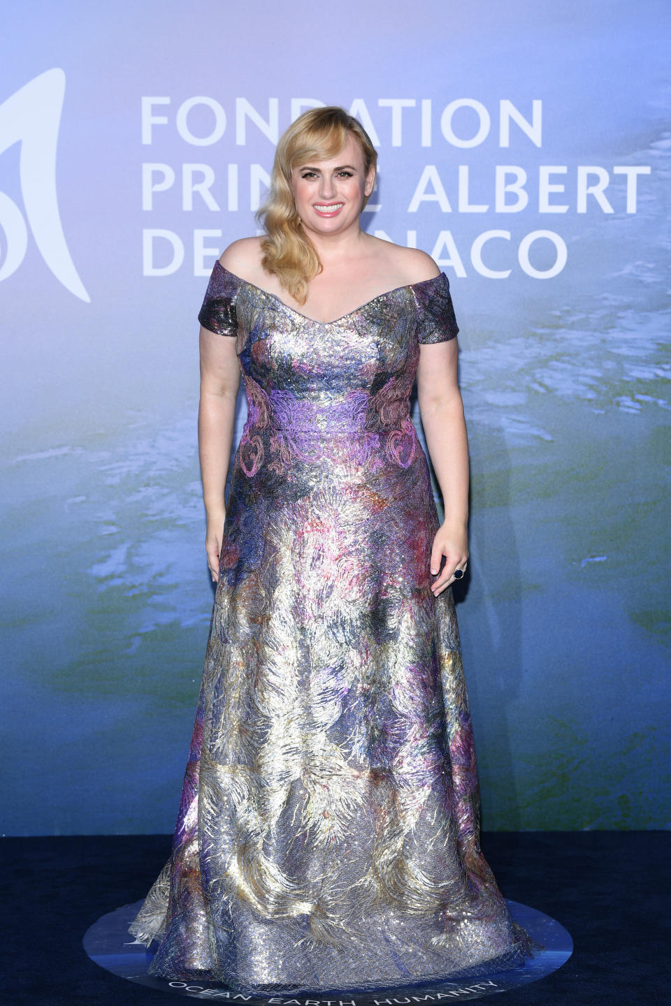 Schluss mit wallenden Stoffmassen: Rebel Wilson stellte ihre schlankere Figur in einem enganliegenden, golden irisierenden Off-Shoulder-Kleid von Rene Ruiz Collection zur Schau. (Bild: Pascal Le Segretain/Getty Images for La Fondation Prince Albert II de Monaco)