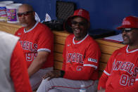 Los Angeles Angels manager Ron Washington, center, laughs as he sits in the dugout with coach Juan Flores, left, and first base coach Bo Porter, right, before a spring training baseball game against the Cincinnati Reds, Sunday, Feb. 25, 2024, in Goodyear, Ariz. (AP Photo/Carolyn Kaster)