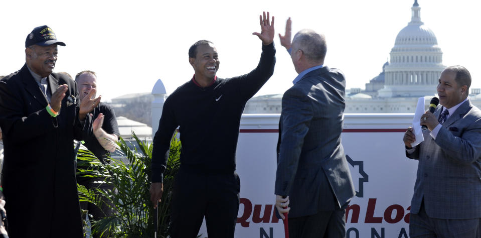 Tiger Woods, center left, gives Quicken Loans Chief Executive Officer Bill Emerson, center right, a high five after Emerson sank a putt during a putting challenge at the Newseum in Washington, Monday, March 24, 2014. Woods and Emerson participated in the putting challenge to have the mortgage payments paid for three military families for one month. Earlier, Woods and Emerson announced that Quicken Loans had signed a multi-year agreement to become the title sponsor of the Quicken Loans National to be played at Congressional in Bethesda, Md., in June. (AP Photo/Susan Walsh)