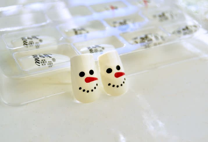 fancy nails with snowman christmas motifs on a white background top view