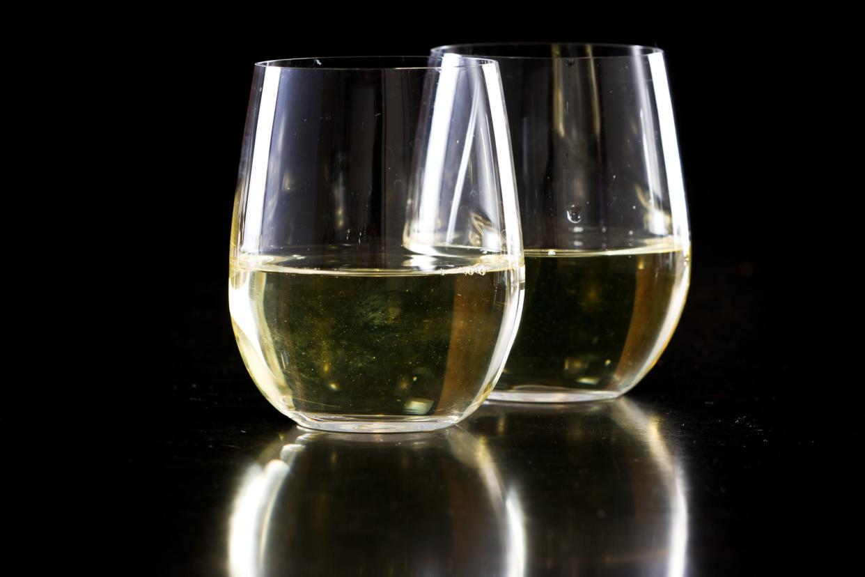 two stemless white wine glasses on a black background