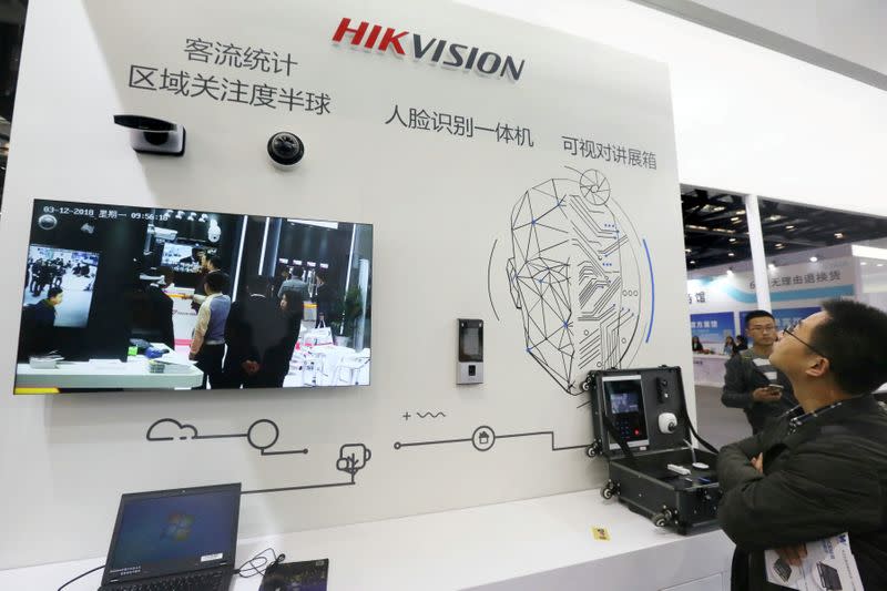 FILE PHOTO: Visitors are seen at a booth of security camera supplier Hikvision Digital Technology during an expo at the National Convention Center in Beijing