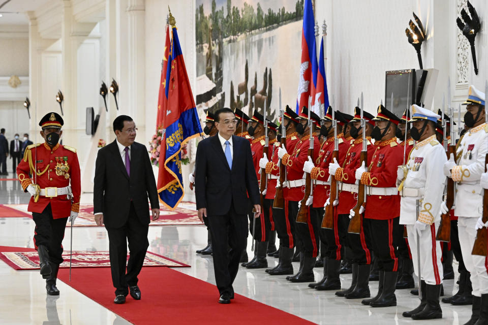 In this photo provided by Cambodia's Government Cabinet, Chinese Premier Li Keqiang, center, and Cambodian Prime Minister Hun Sen, center left, review honorary troops during a welcome meeting at Peace Palace in Phnom Penh, Cambodia, Wednesday, Nov. 9, 2022. (Kok Ky/Cambodia's Government Cabinet via AP)