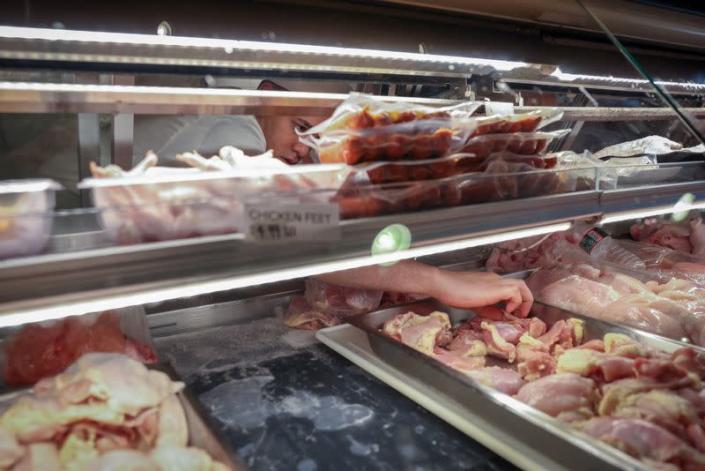 A worker reaches for meat at a butcher shop in Manhattan, New York City