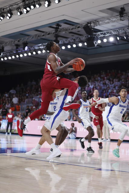 In a photo provided by Bahamas Visual Services, Arkansas's Khalif Battle, top center, jumps past Memphis' Jahvon Quinerly during an NCAA college basketball game in the Battle 4 Atlantis at Paradise Island, Bahamas, Thursday, Nov. 23, 2023. (Tim Aylen/Bahamas Visual Services via AP)