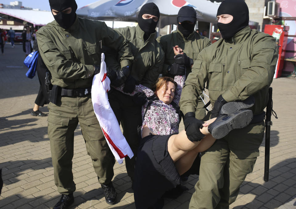 Police officer detain a woman with an old Belarusian national flag during an opposition rally to protest the official presidential election results in Minsk, Belarus, Saturday, Sept. 26, 2020. Hundreds of thousands of Belarusians have been protesting daily since the Aug. 9 presidential election. (AP Photo/TUT.by)