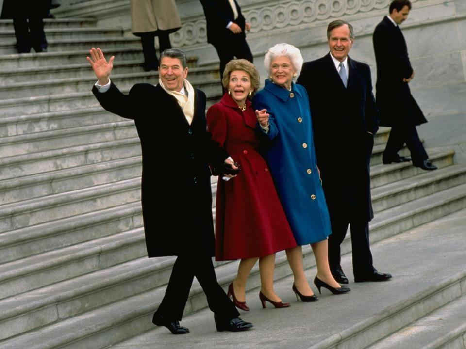 The two couples walk down the Capitol steps with Nancy in a dark red coat and Barbara in a blue coat.