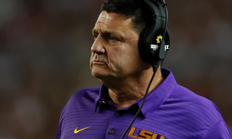 LSU football coach Ed Orgeron wearing a headset and a concerned look.