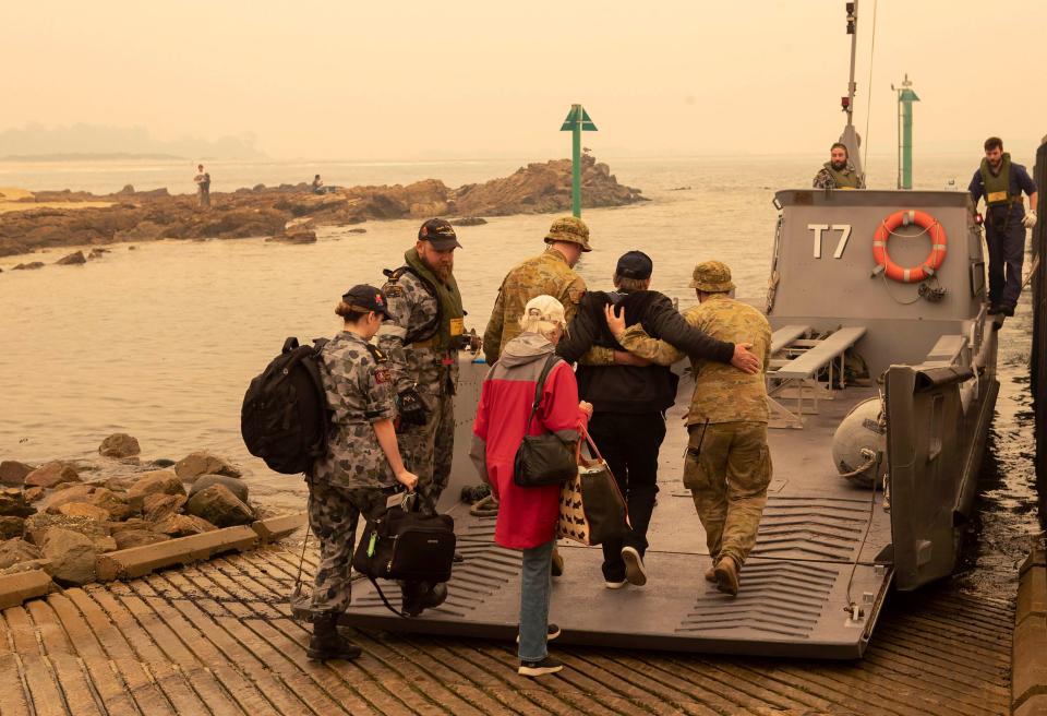 In this photo released by the Australian Department of Defense, evacuees board landing craft to be ferried out to the navy's HMAS Choules, Friday, Jan. 3, 2020, in Mallacoota, Victoria, Australia.