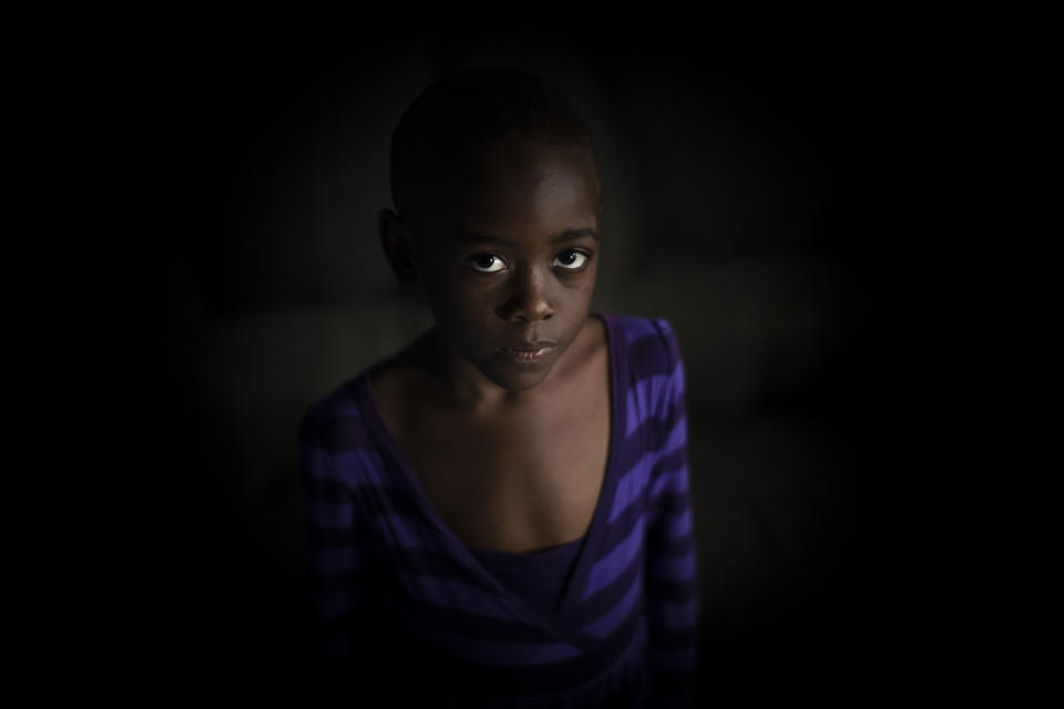 In this photo taken Wednesday, Nov. 6, 2019, Ange Mucyo Izere, 6, who has bone marrow cancer and takes oral liquid morphine for her pain, stands inside her home in the Gitega neighborhood of the capital Kigali, Rwanda. While people in rich countries are dying from overuse of prescription painkillers, people in Rwanda and other poor countries are suffering from a lack of them, but Rwanda has come up with a solution to its pain crisis - it's morphine, which costs just pennies to produce and is delivered to households across the country by public health workers. (AP Photo/Ben Curtis)