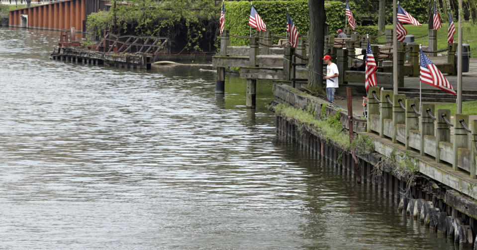 A man fishes off a dock on the Cuyahoga River, Tuesday, May 28, 2019, in Cleveland. Fifty years after the Cuyahoga River's famous fire, a plucky new generation of Cleveland artists and entrepreneurs has turned the old jokes about the “mistake on the lake” into inspiration and forged the decades of embarrassment into a fiery brand of local pride. (AP Photo/Tony Dejak)