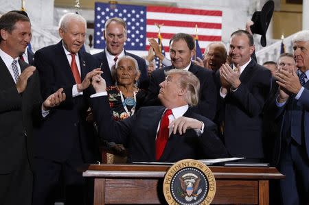 U.S. President Donald Trump hands a pen used to sign an executive order to Sen. Orrin Hatch (R-UT) after announcing big cuts to Utah's sprawling wilderness national monuments at the Utah State Capitol in Salt Lake City, Utah, U.S., December 4, 2017. REUTERS/Kevin Lamarque
