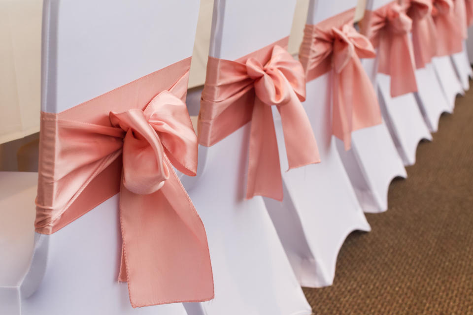 Row of wedding chairs with pink satin bows on the backrests