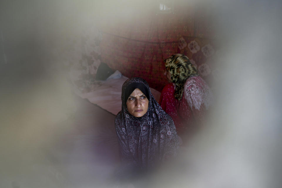 Ola Nassar, 41, who was displaced by the Israeli bombardment of the Gaza Strip, sits at a makeshift tent camp in Khan Younis, southern Gaza Strip, Thursday, July 4, 2024. Over nine months of war between Israel and Hamas, Palestinian families in Gaza have been uprooted repeatedly, driven back and forth across the territory to escape the fighting. Each time has meant a wrenching move to a new location and a series of crowded, temporary shelters. (AP Photo/Abdel Kareem Hana)
