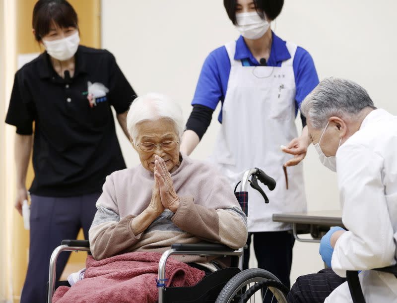 An elderly woman gestures to express gratitude after receiving a coronavirus disease (COVID-19) vaccination in Itami, western Japan