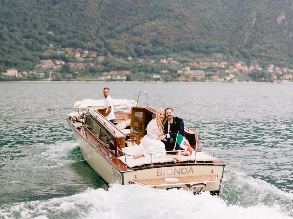 A couple in a boat with mountains surrounding them.