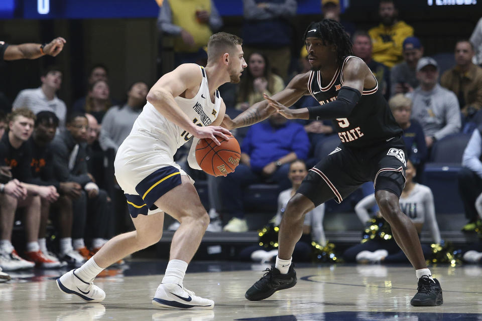 West Virginia guard Erik Stevenson, left, is defended by Oklahoma State guard Caleb Asberry, right, during the first half of an NCAA college basketball game on Monday, Feb. 20, 2023, in Morgantown, W.Va. (AP Photo/Kathleen Batten)