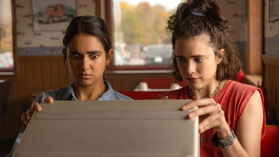 Jamie and Marian looking into a briefcase with concern in a scene from "Drive-Away Dolls"