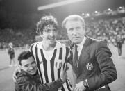 FILE - In this May 30, 1985 file photo, Juventus Turin soccer player Paolo Rossi is embraced by a fan as he stands with Juventus team manager Giovanni Trapattoni on the field of the Brussels Heysel Stadium, May 30, 1985 after winning the European Champions Cup beating FC Liverpool 1-0. Rossi, the star of Italy’s World Cup-winning team in 1982, has reportedly died at age 64. He was the leading scorer in the '82 World Cup and was also FIFA's player of the year. (AP Photo)