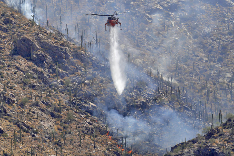 A Wildfire air attack crew battles the Bighorn Fire along the western side of the Santa Catalina Mountains, Friday, June 12, 2020, in Tucson, Arizona. Hundreds of homes on the outskirts of Tucson remain under an evacuation notice as firefighters work to keep the wildfire from moving downhill from canyons and ridges in the Coronado National Forest. (AP Photo/Matt York)