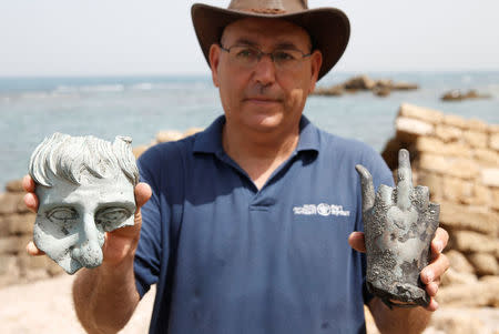 An Israel Antiquities Authority (IAA) employee holds parts of statues, which the IAA estimates to be around 1600 years old, after they were recovered from a merchant ship in the ancient harbor of the Caesarea National Park May 16, 2016. REUTERS/ Baz Ratner