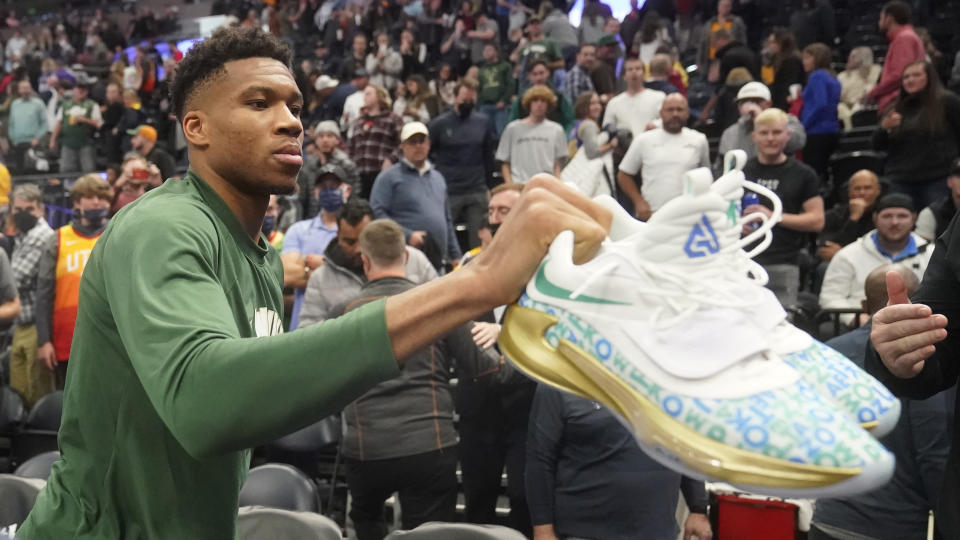 Milwaukee Bucks forward Giannis Antetokounmpo hands his shoes to a fan following the team's preseason NBA basketball game against the Utah Jazz on Wednesday, Oct. 13, 2021, in Salt Lake City. (AP Photo/Rick Bowmer)