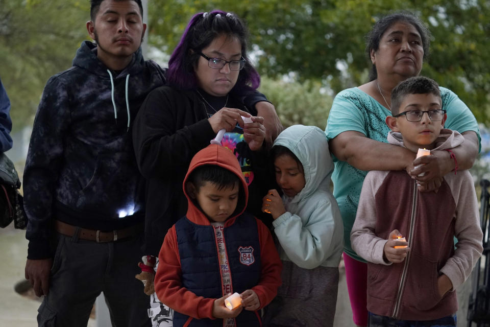 Eric Martinez, 6, front left, Isabella Southerland, 7, front center, and Andrew Martinez, 9, front right, stand with their family as they take part in a community vigil for the dozens of people have been found dead Monday in a semitrailer containing suspected migrants, Tuesday, June 28, 2022, in San Antonio. (AP Photo/Eric Gay)