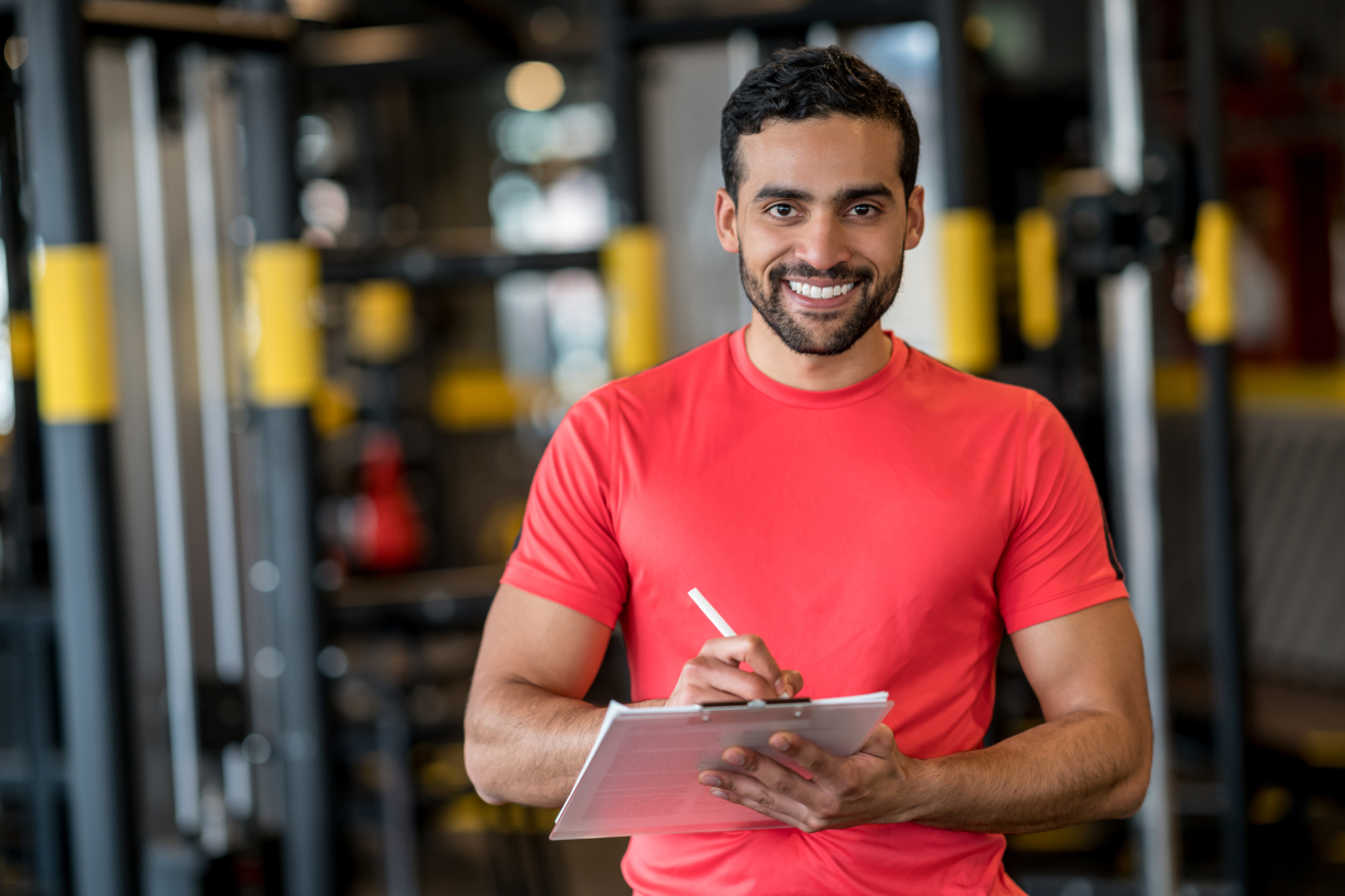 Smiling personal trainer holding a clipboard