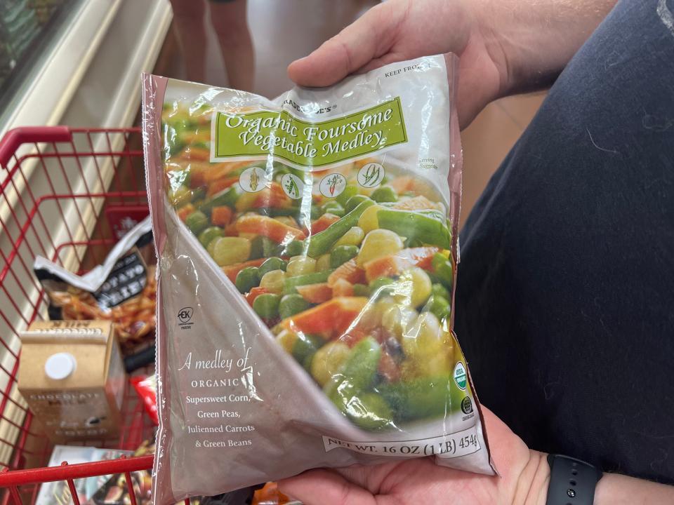 The writer holds a bag of frozen mixed vegetables