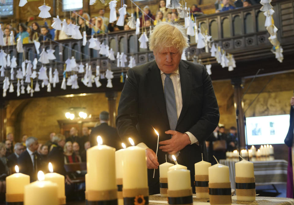 Former prime minister Boris Johnson lights one of the 52 candles - one for each week of the war - during an ecumenical prayer service at the Ukrainian Catholic Cathedral in London, to mark the one year anniversary of the Russian invasion of Ukraine, Friday Feb. 24, 2023. (Yui Mok/PA via AP)