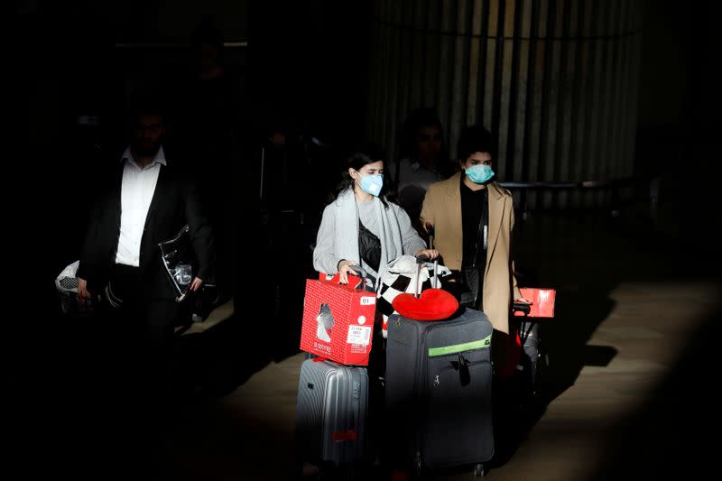 FILE PHOTO: Travellers pull their suitcases while wearing masks in a terminal at Ben Gurion International airport in Lod, near Tel Aviv, Israel
