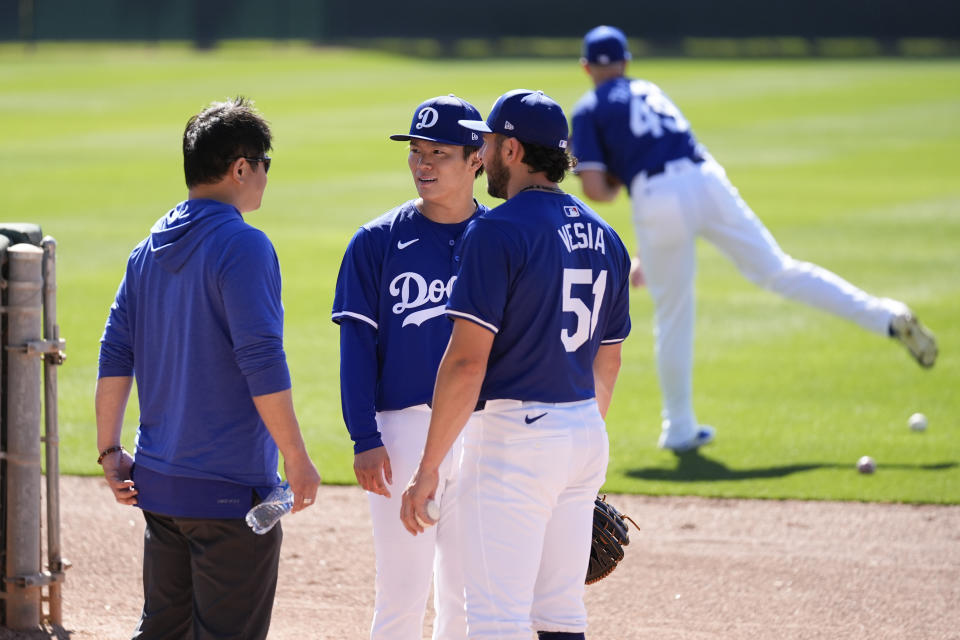 Los Angeles Dodgers starting pitcher Yoshinobu Yamamoto (18) and his interpreter Yoshihiro Sonoda, left, greet relief pitcher Alex Vesia (51) during spring training baseball workouts at Camelback Ranch in Phoenix, Monday, Feb. 19, 2024. (AP Photo/Ashley Landis)