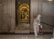 After each prayer session, workers in full-body protective suits sanitize any surface that may have been touched at the BAPS Shri Swaminarayan Mandir, also known as the Neasden Temple, in London on Friday, July 3, 2020. The magnificent temple of carved stone constructed according to ancient Vedic architectural texts usually welcomes thousands of visitors a day but now gets just a trickle of devotees who book appointments online first to keep the crowds down. (AP Photo/Elizabeth Dalziel)